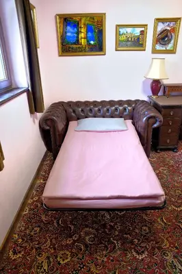 a bed in a room with a leather couch at A cosy house near the city centre in Glasgow