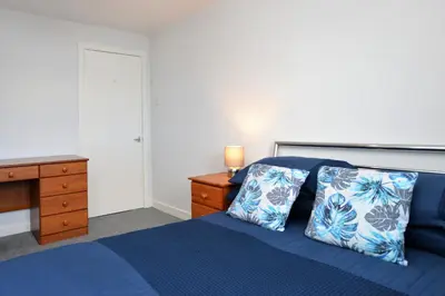 a bedroom with a blue bed and a wooden desk at Anchor View in Ardrishaig