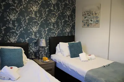two beds in a room with blue and white wallpaper at PREMIER - Fleming Apartment in Hamilton