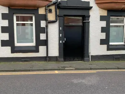 a house with a black door and two windows at Nelson st (MAYBOLE) in Largs