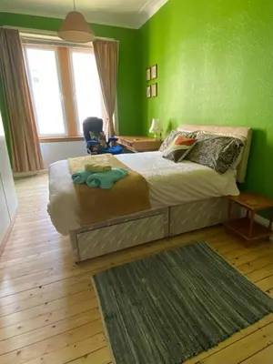 a bedroom with a bed with a green wall at Lovely flat overlooking the Clyde in Gourock