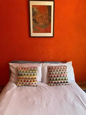 a bed with two pillows in a bedroom with an orange wall at Lovely flat overlooking the Clyde in Gourock