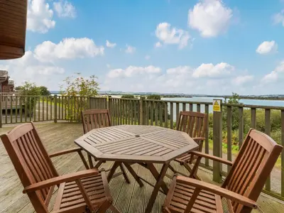 a table and chairs on a deck with a view of the water at Chalet Loch Side Lodge 8 by Interhome in Kinross