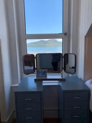 a room with a desk with a mirror and a window at This must be the place - Arran, Lamlash in Lamlash