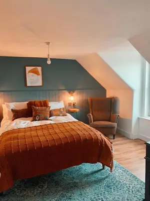 a bedroom with a large bed and a chair at This must be the place - Arran, Lamlash in Lamlash