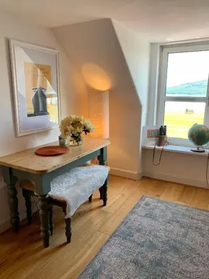 a room with a table with a vase of flowers on it at This must be the place - Arran, Lamlash in Lamlash