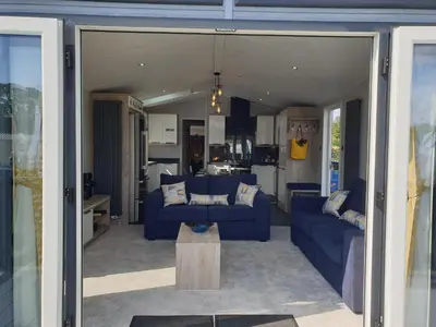 a living room with two blue couches and a kitchen at Machrihanish Holiday Park in Campbeltown