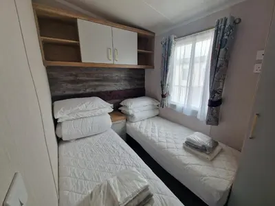 a small room with two beds and a window at Machrihanish Holiday Park in Campbeltown
