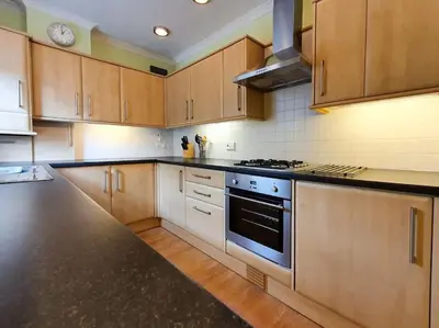 a kitchen with wooden cabinets and a stove top oven at Parkgate Apartment - Near M90, Amazon, Edinburgh in Rosyth