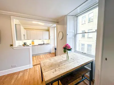 a vase of flowers sitting on a wooden table in a kitchen at Rose Street's Hidden Treasure- 2Bed Newly Refurbished Apt in Edinburgh