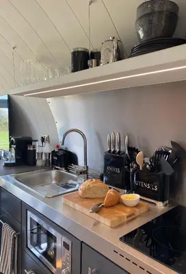 a kitchen with a sink and a cutting board with bread at Raven's Gully - Brodick, Isle Of Arran in Brodick