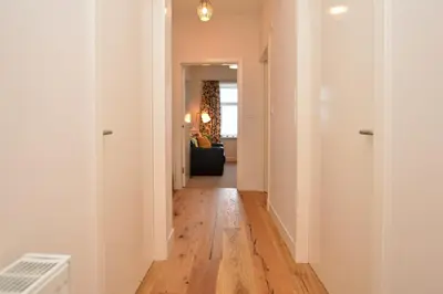 a hallway leading to a living room with wood floors at Pedals and Paddles in Innellan