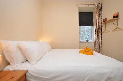 a bedroom with a white bed with a yellow towel on it at Pedals and Paddles in Innellan