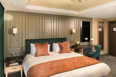 a bedroom with a large bed with a green headboard at Brig o' Doon House Hotel in Ayr