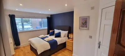 a bedroom with a bed with blue walls and a window at Laighdykes Guest Cottage in Saltcoats