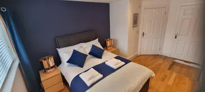 a bedroom with a bed with blue and white pillows at Laighdykes Guest Cottage in Saltcoats