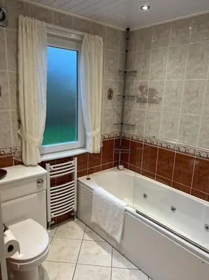 a bathroom with a tub and a toilet and a window at Stunning views in Lochgoilhead