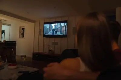 a woman sitting in a living room watching a television at The Penthouse Suite - Luxury Like No Other in Glasgow