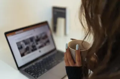 a woman holding a cup and a laptop computer at The Penthouse Suite - Luxury Like No Other in Glasgow