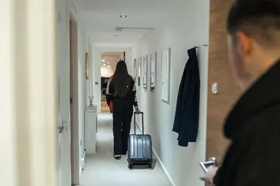 a woman walking down a hallway with a suitcase at The Penthouse Suite - Luxury Like No Other in Glasgow