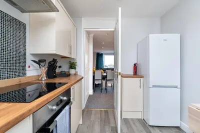 a kitchen with white cabinets and a dining room at Lovely 3-bedroom flat with free parking in Bridge of Allan