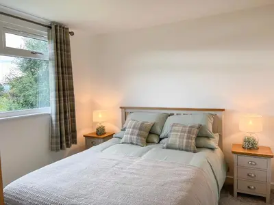 a bedroom with a bed with two night stands and a window at Ciaran Cottage in Stron-fearnan