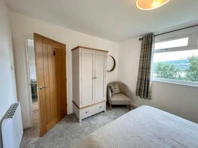 a bedroom with a bed and a cabinet and a chair at Ciaran Cottage in Stron-fearnan