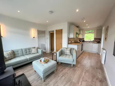 a living room with a couch and chairs and a kitchen at Ciaran Cottage in Stron-fearnan