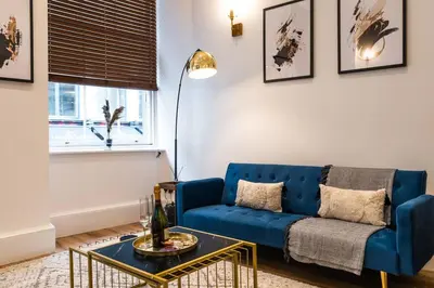 a living room with a blue couch and a table at The City Escape - 5* stay in the heart of Glasgow! in Glasgow