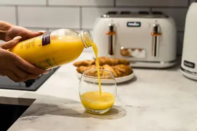 a person pouring a glass of orange juice from a bottle at The City Escape - 5* stay in the heart of Glasgow! in Glasgow
