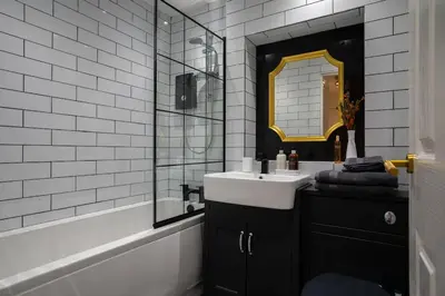 a black and white bathroom with a sink and a mirror at The City Escape - 5* stay in the heart of Glasgow! in Glasgow