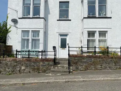 a white house with a fence in front of it at St John's Flat Spacious Accomodation in Dalry