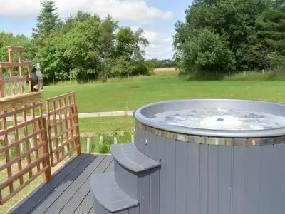 a hot tub on a deck with two chairs at Pentland Pod - Cottage in Penicuik