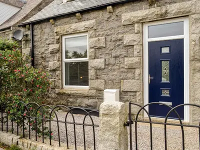 a blue door on a stone house with a fence at Park Crescent - Cottage in Creetown