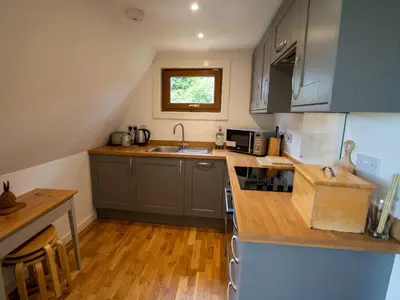 a kitchen with gray cabinets and a wooden floor at Ledi - Cottage in Linlithgow