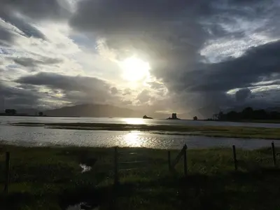 a sunset over a body of water with the sun shining at Dalnafeidh Beag - Cottage in Portnacroish