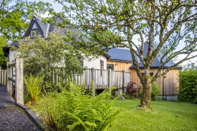 a house with a fence and a tree in the yard at Kinlochlaich Tree House in Appin