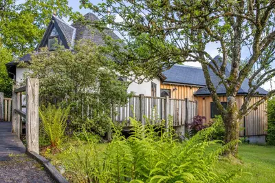 a house with a wooden fence in the yard at Kinlochlaich Tree House in Appin