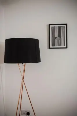 a black lamp sitting next to a wall with a picture at Tower Square House in Alloa