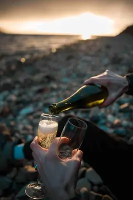 a person pouring a bottle of wine into a glass at The Boathouse pod in Onich