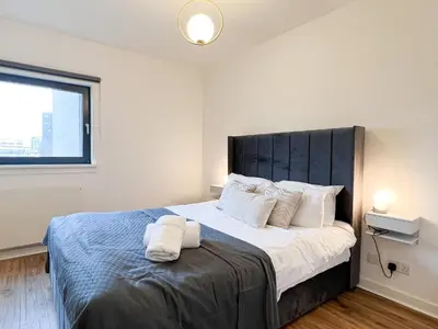 a bedroom with a large bed with white pillows at Lovely two bed apartment in Finnieston in Glasgow