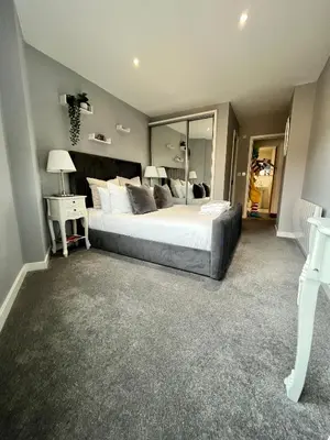 a bedroom with a large bed and a mirror at Glas Go Executive 2-Bedroom Apartment near OVO Hydro Free Parking in Glasgow