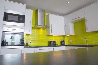 a kitchen with white cabinets and yellow tiles at Glas Go Executive 2-Bedroom Apartment near OVO Hydro Free Parking in Glasgow