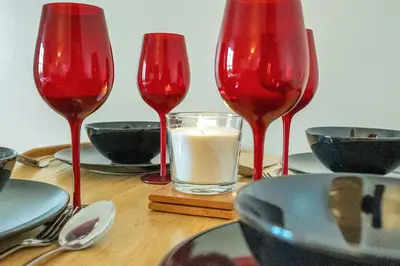three red wine glasses sitting on a table with a candle at Modern 1BR flat - free parking + lift in Edinburgh