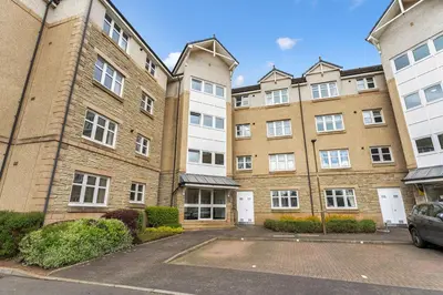an apartment building with a parking lot in front of it at Modern 1BR flat - free parking + lift in Edinburgh