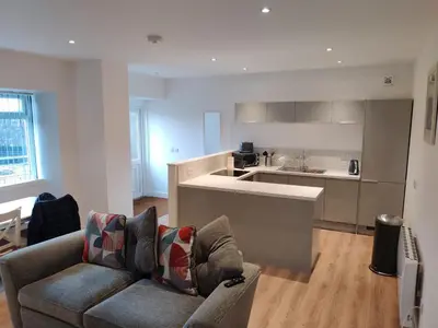 a living room with a couch and a kitchen at No 7 Westbay Apartment in Oban