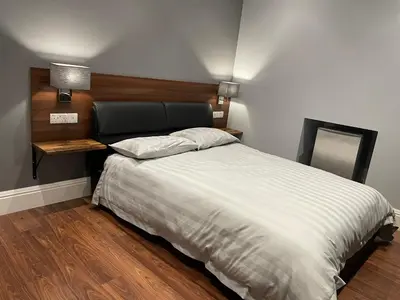 a bedroom with a bed with a headboard and a mirror at Laurieston Inn in Falkirk