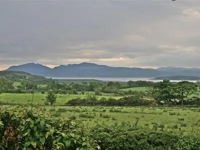 a green field with mountains in the background at The Coach House at Stewart Hall in Rothesay