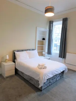 a bedroom with a bed with a stuffed animal on it at Comfortable 4 bed Apt in Paisley Next to Station in Paisley