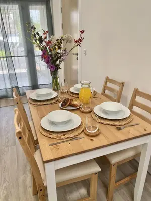 a wooden table with plates and glasses and flowers on it at The Coorie in Bargrennan